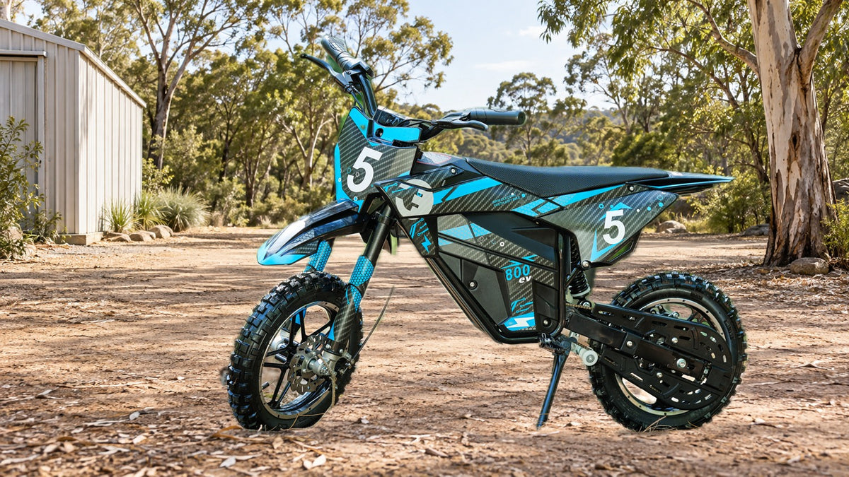Illustrative campaign image of a complete blue and black Outrider bike in a rural shed setting.